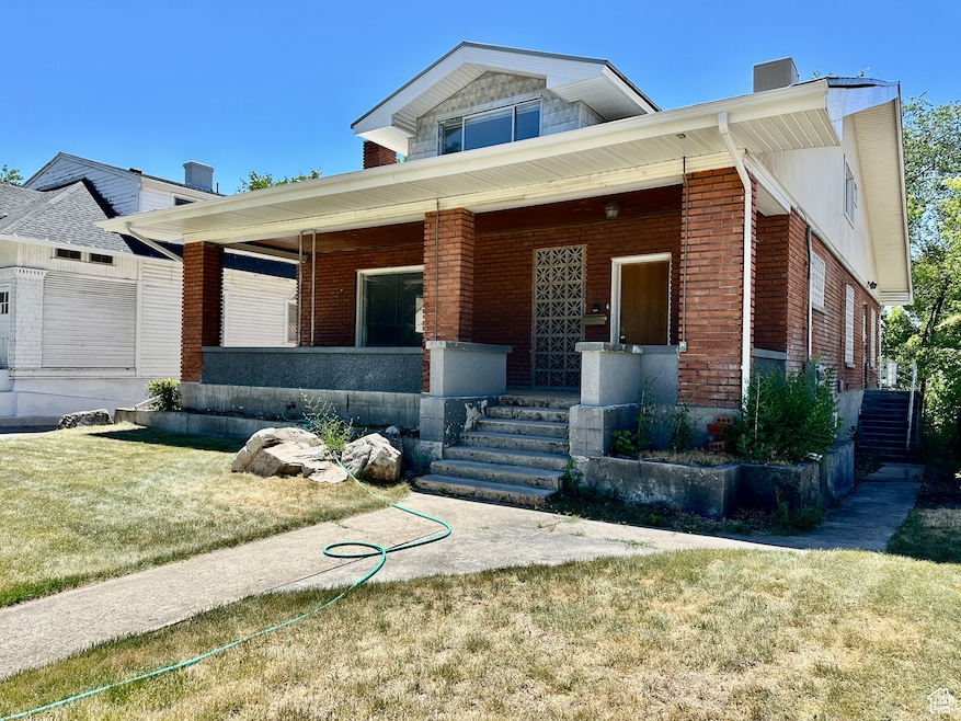 View of front of property with covered porch, brick siding, and a front lawn