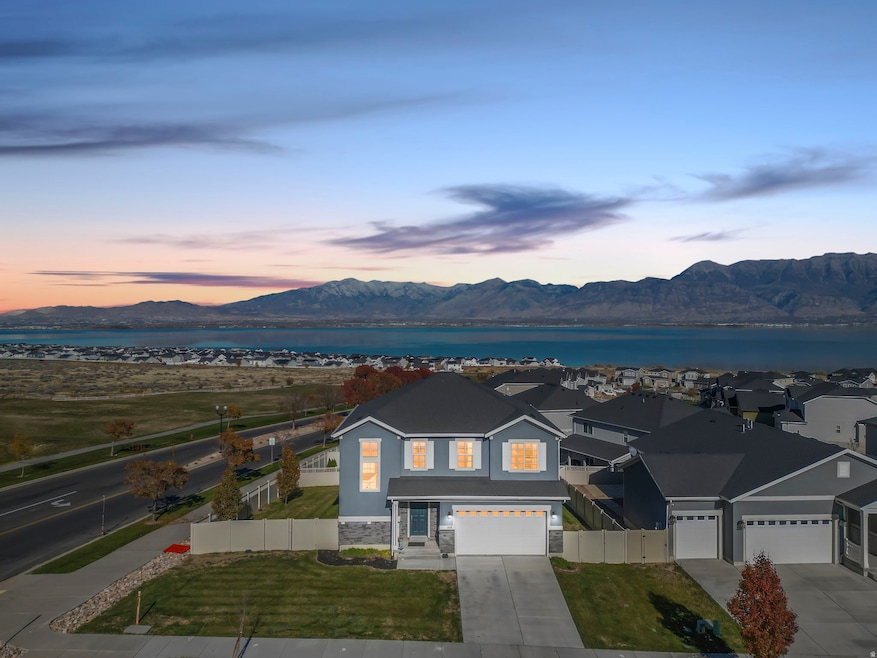 View of front of home with stone siding, concrete driveway, stucco siding, a water and mountain view, and an attached garage