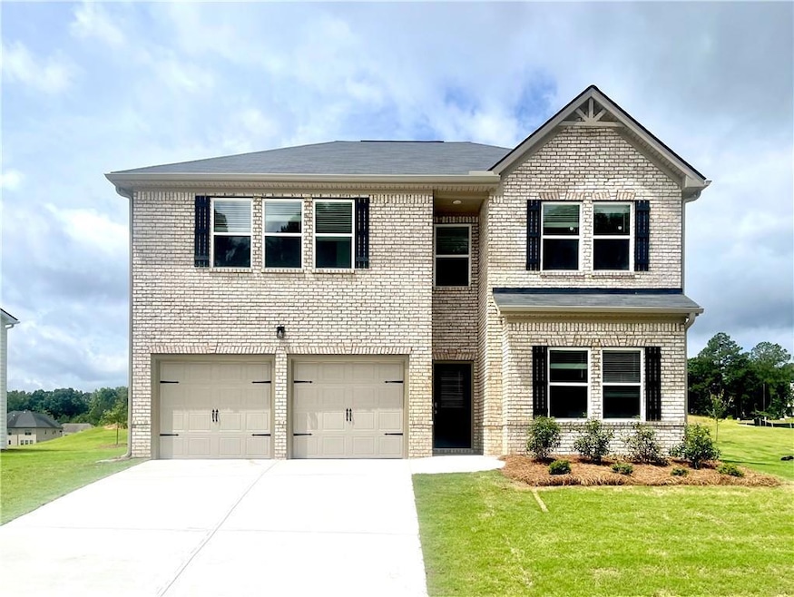 View of front of home with brick siding, an attached garage, a front lawn, and driveway