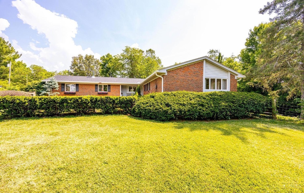 Outside is a 30’x 50’ pole barn with 20’ x 30’ insulated room perfect for a shop or workspace.  The property has been lovingly cared for over the years, showcasing meticulous attention to detail. Thoughtful additions like a hidden dog door in the garage, a golf tee, fruit orchards, a decorative koi pond, and a fenced front yard add charm. The walkout basement enhances the space, while the surrounding natural beauty creates a paradise for nature enthusiasts. You’ll find well-maintained trails through the woods with views of a creek, groves of Paw Paw and Walnut trees, and a milkweed monarch habitat. The outdoor area also boasts an established fire pit, and small structures. Inside, the connection to nature continues with stunning views from the sunroom, back patio, deck, gardens, and front porch—an ideal setting for those seeking a sustainable, nature-centered lifestyle.