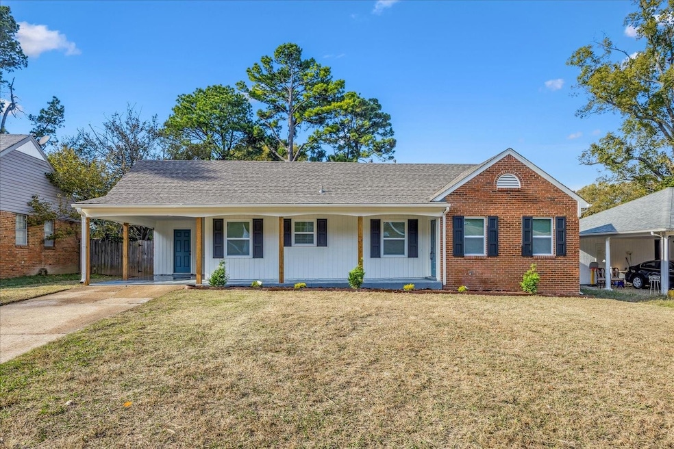 View of front of house with covered porch, a front lawn, roof with shingles, driveway, and brick siding