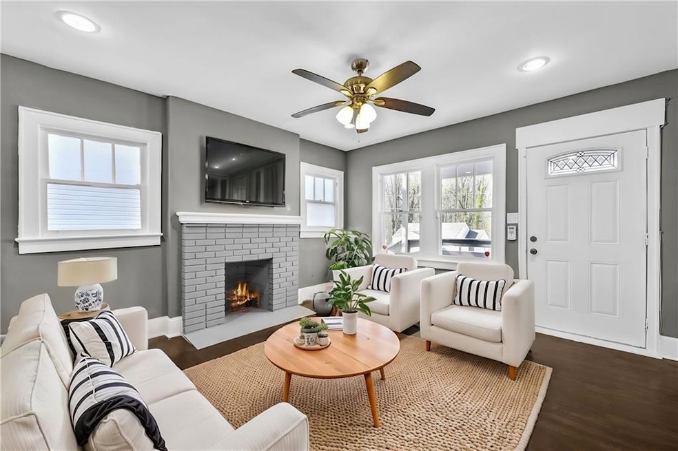 Living room with ceiling fan, baseboards, a brick 