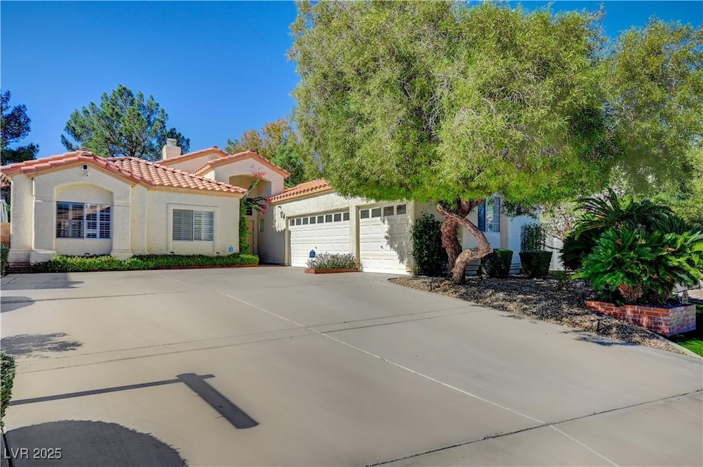 View of front of property with stucco siding, driveway, a tile roof, a chimney, and an attached garage