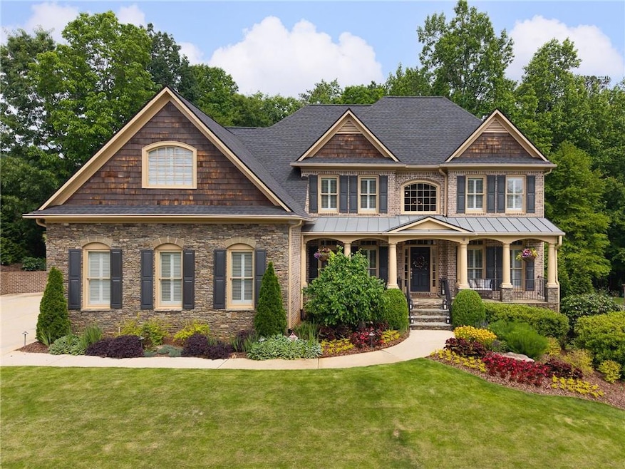View of front of property featuring a shingled roof, a front yard, a porch, and stone siding