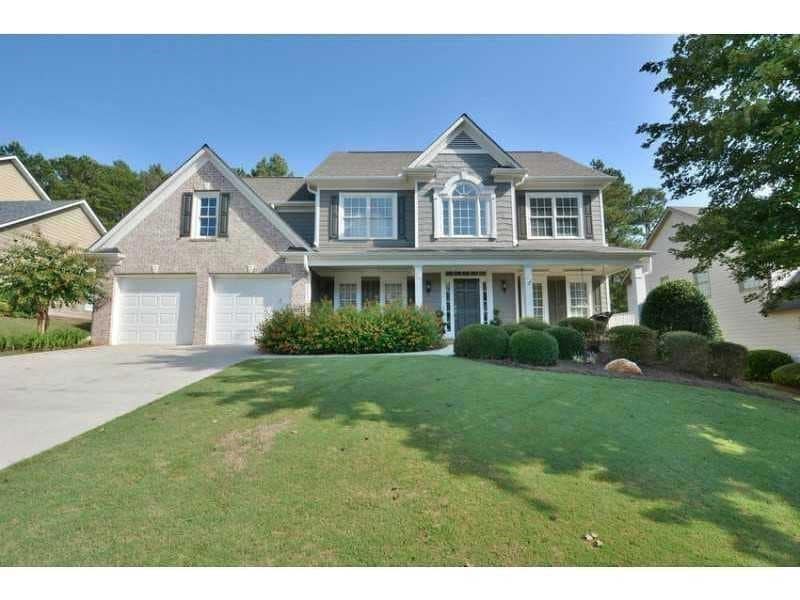 Colonial home with a front yard, driveway, covered porch, and a garage