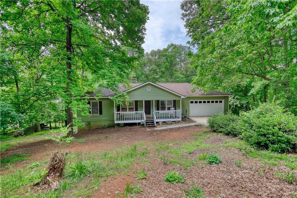Single story home with covered porch, a garage, dirt driveway, and a chimney