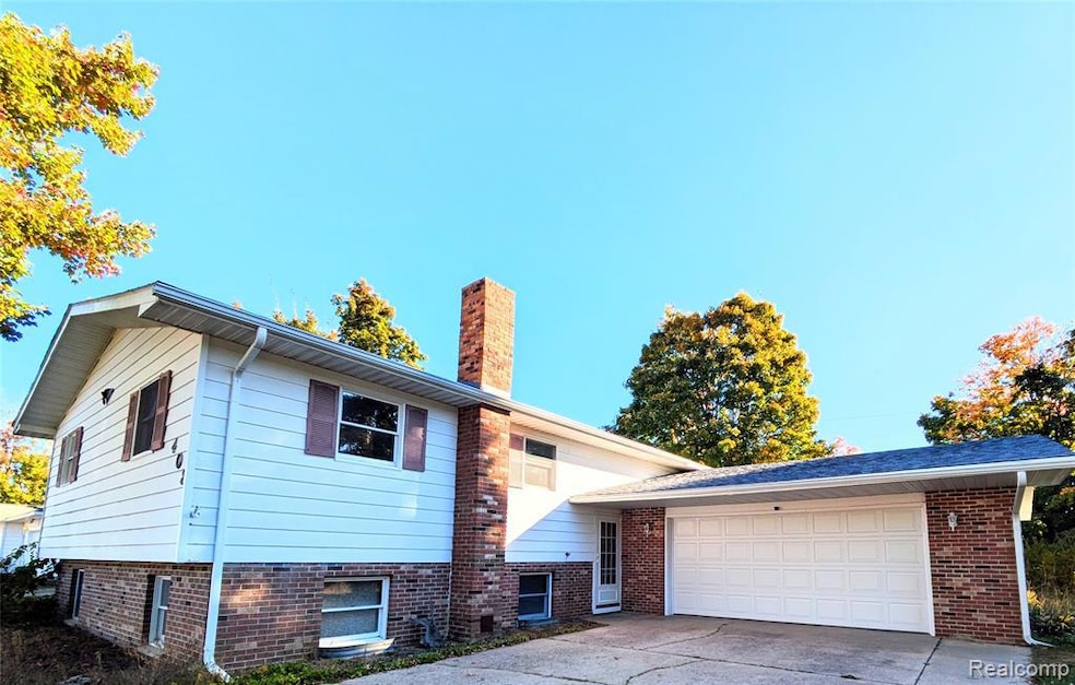 View of front facade featuring a chimney, concrete driveway, and a garage