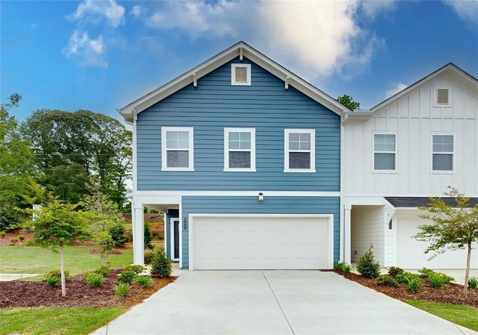 View of front facade featuring board and batten siding, an attached garage, and concrete driveway