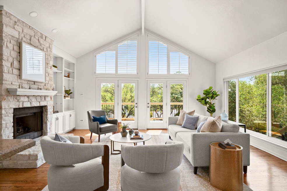 Living room featuring a fireplace, wood finished floors, high vaulted ceiling, and built in shelves