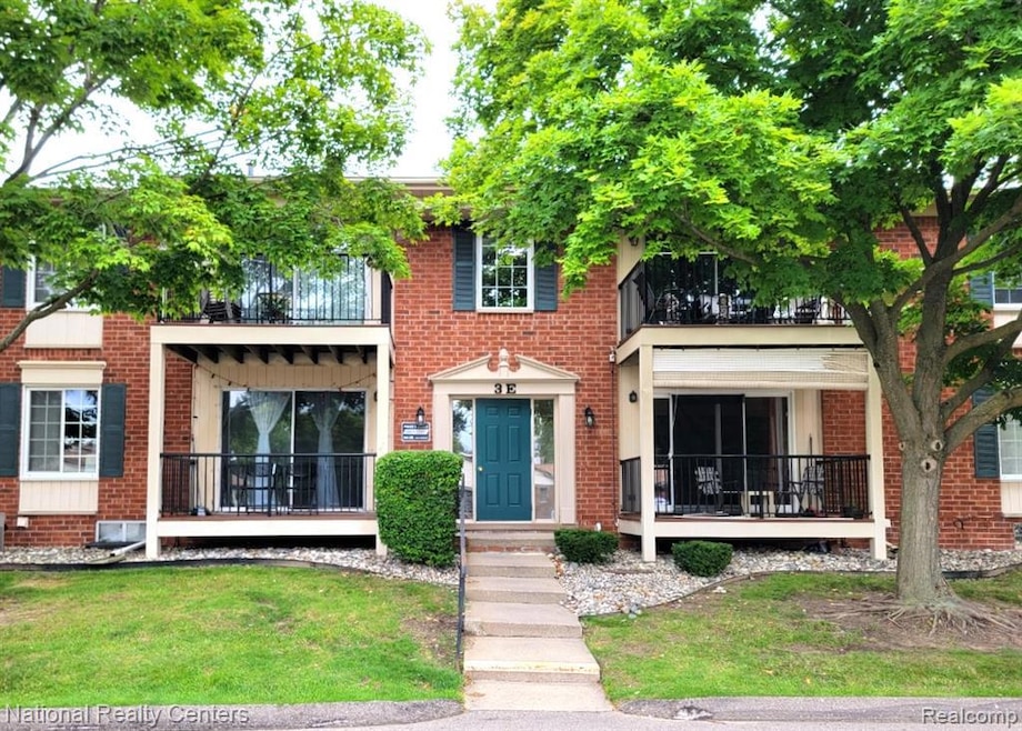 View of front facade featuring a balcony, brick siding, and a front lawn