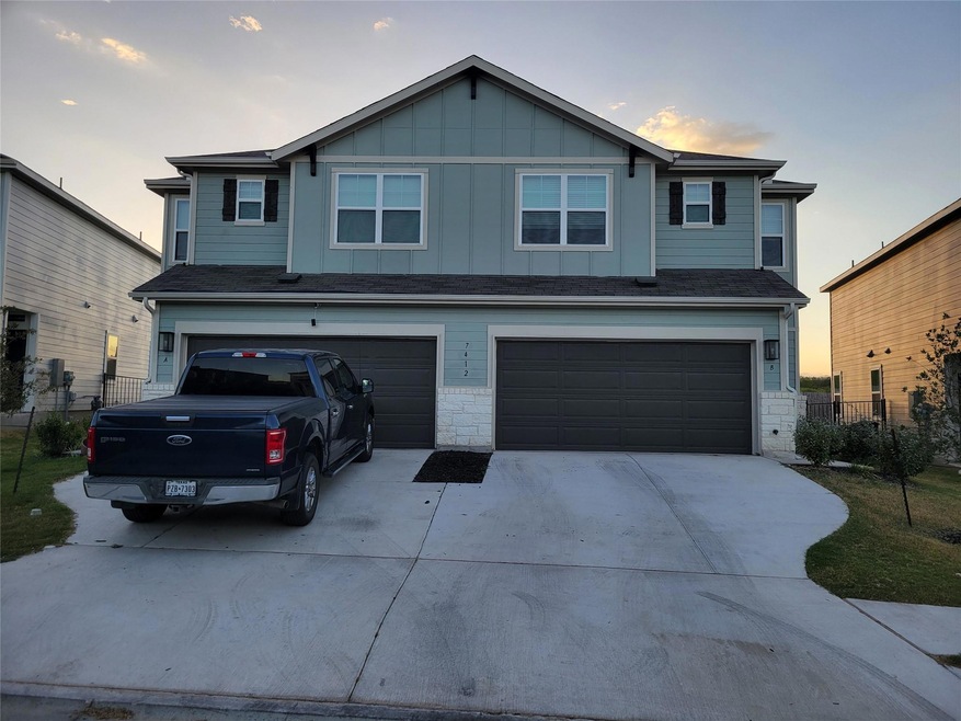 View of front of house with driveway, board and batten siding, stone siding, and an attached garage