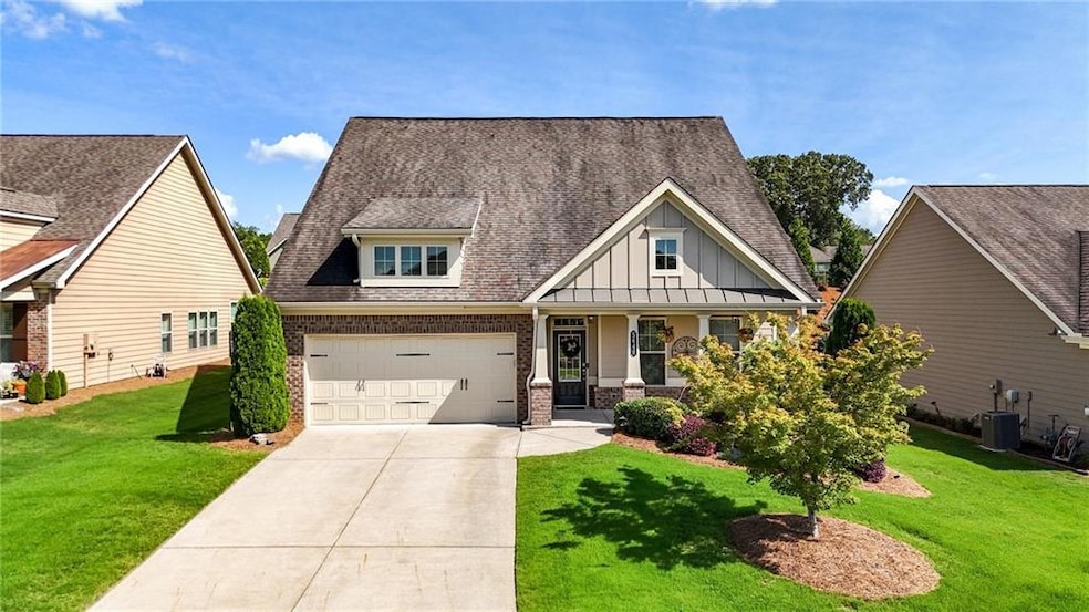 Craftsman house with board and batten siding, driveway, a front lawn, and covered porch