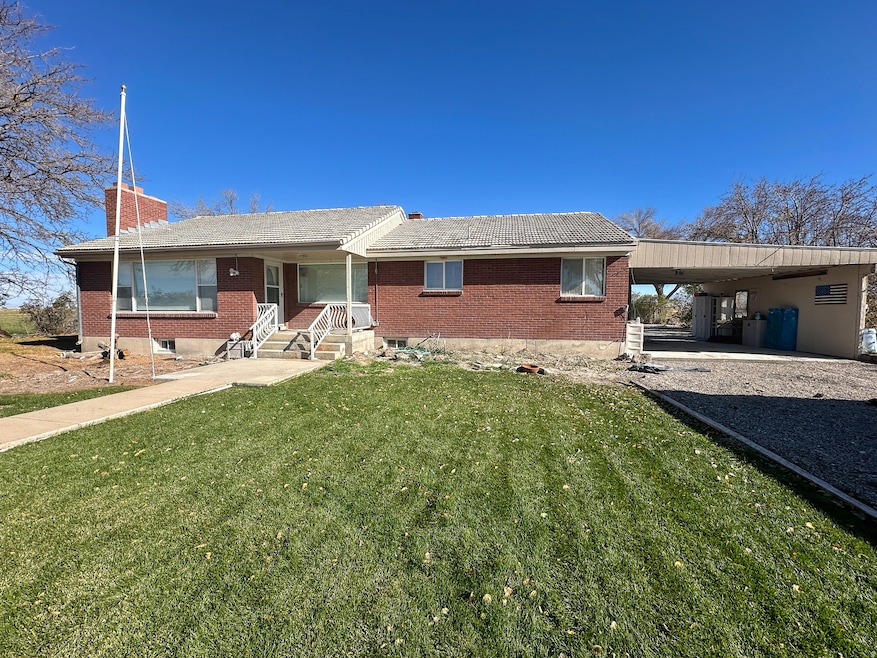 Ranch-style house featuring brick siding, a front lawn, a carport, a chimney, and driveway