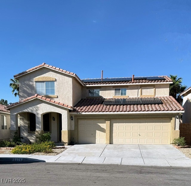 Mediterranean / spanish-style house featuring roof mounted solar panels, stucco siding, concrete driveway, and a tile roof