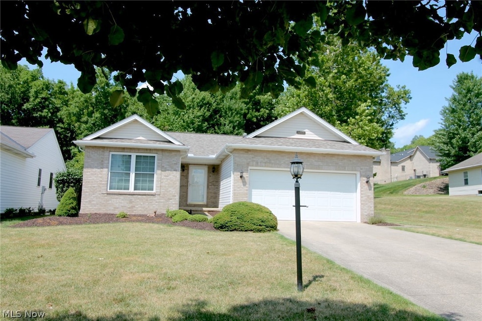 Single story home with a garage and a front lawn