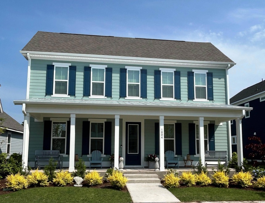 Colonial home featuring a porch and roof with shingles