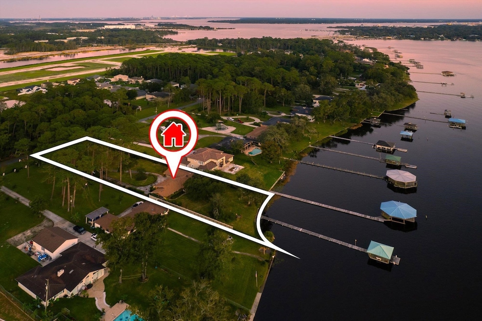 Aerial view of property and surrounding area with property boundaries highlighted, a large body of water, and nearby suburban area