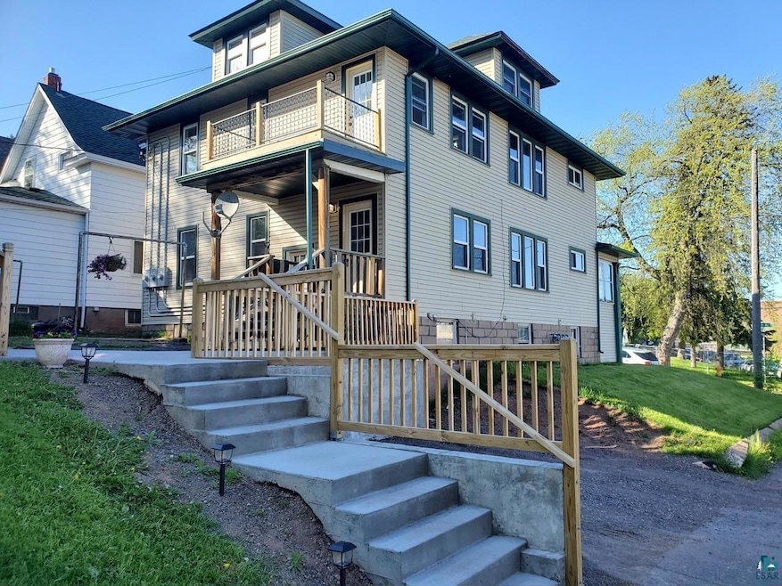 Rear view of house featuring a balcony, a yard, and a porch