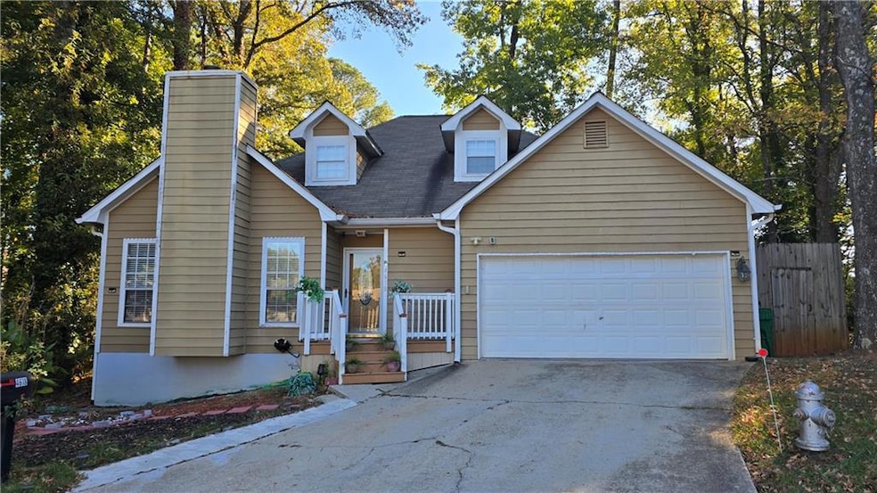View of front facade with driveway, a chimney, a shingled roof, and an attached garage