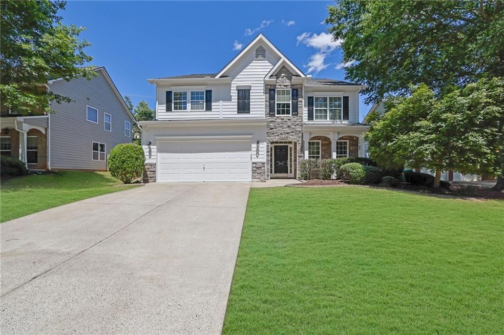 Traditional-style house featuring stone siding, concrete driveway, a garage, and a front yard