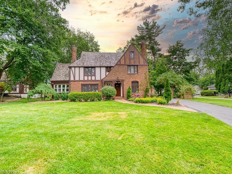 Classic Brick Tudor Revival exterior features soldier course brick working, stone application, slate roof, stucco accent and wood accent trim.