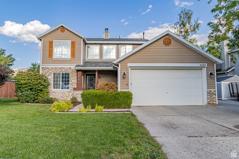 Traditional home featuring stone siding, concrete driveway, a chimney, and an attached garage