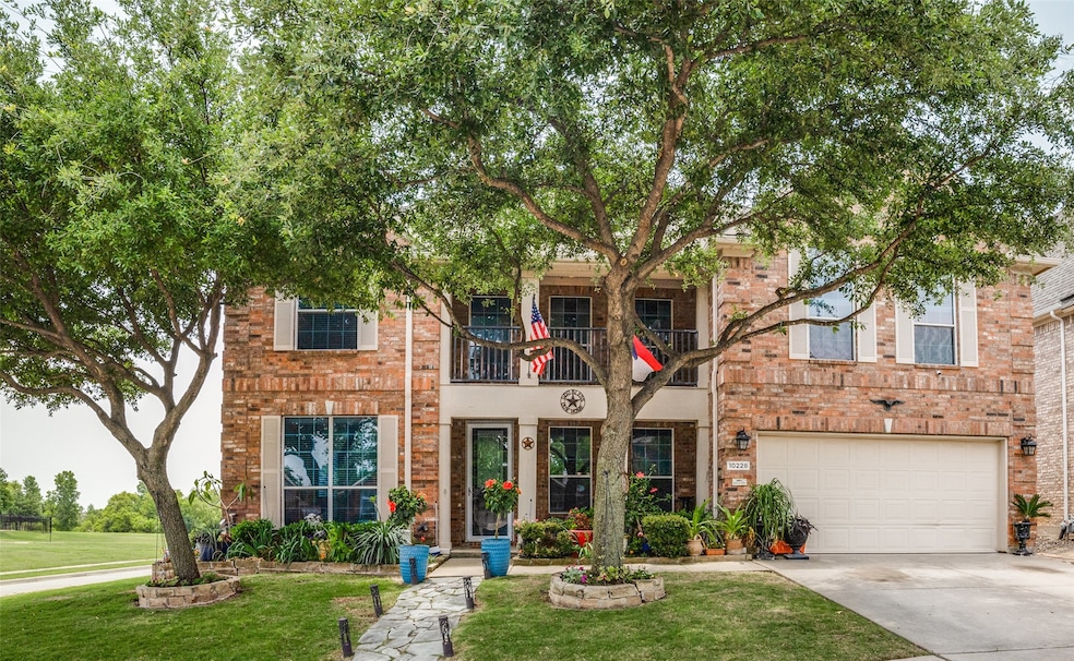 View of front of property featuring a balcony, a front yard, concrete driveway, brick siding, and a garage