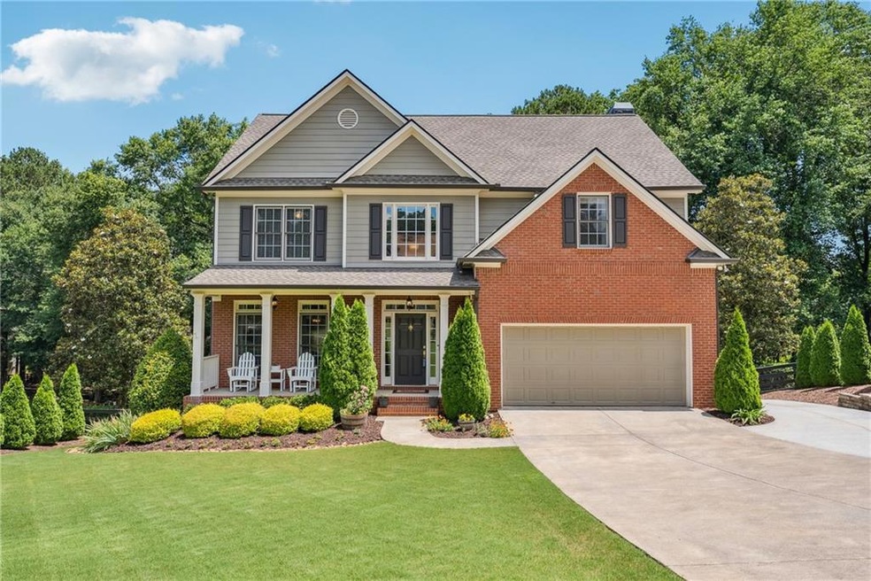 View of front of house featuring driveway, a garage, covered porch, brick siding, and a front yard
