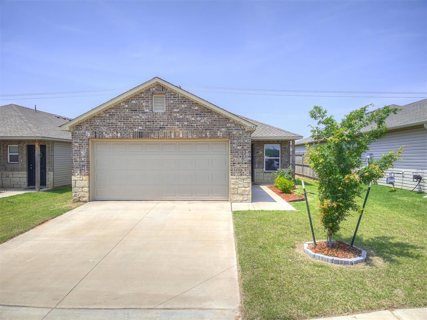 Single story home featuring brick siding, concrete driveway, a front yard, an attached garage, and roof with shingles
