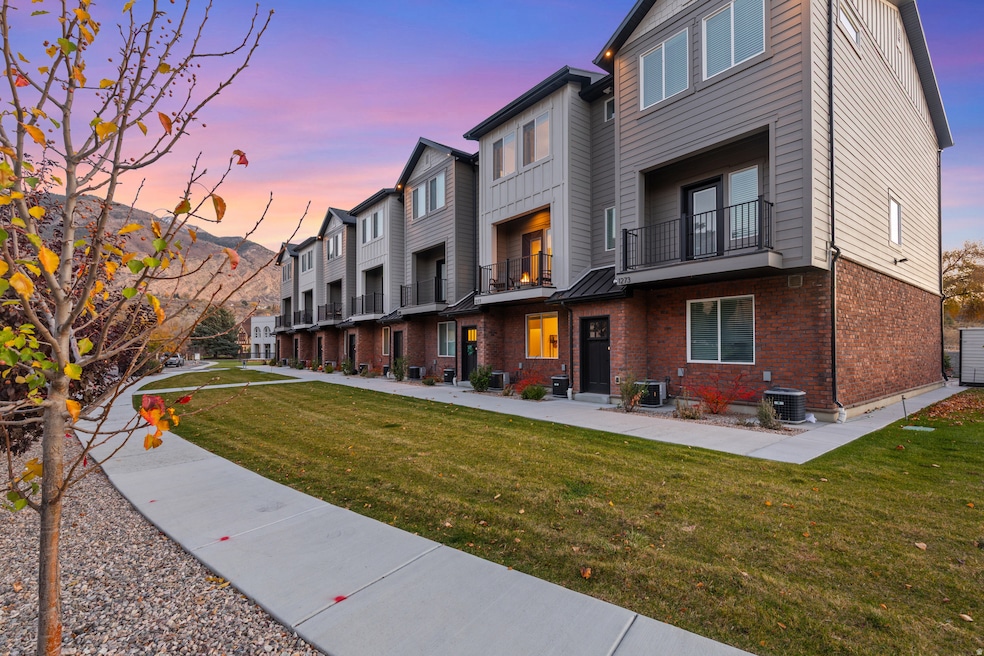 Back of property featuring brick siding, a balcony, a residential view, and a lawn