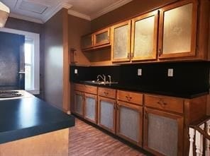 Kitchen featuring dark countertops, brown cabinetry, crown molding, and dark wood-style floors