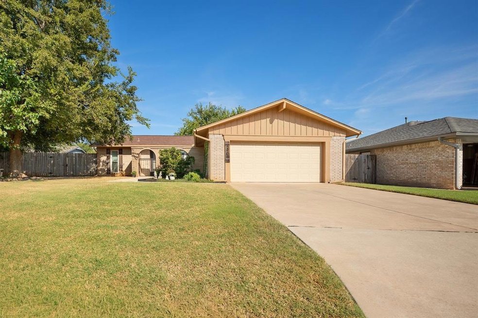 Single story home featuring brick siding, driveway, a garage, and a gate