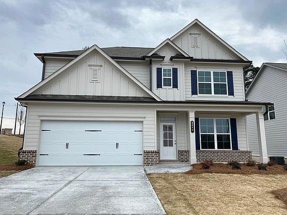 Craftsman-style home featuring board and batten siding, brick siding, driveway, and covered porch