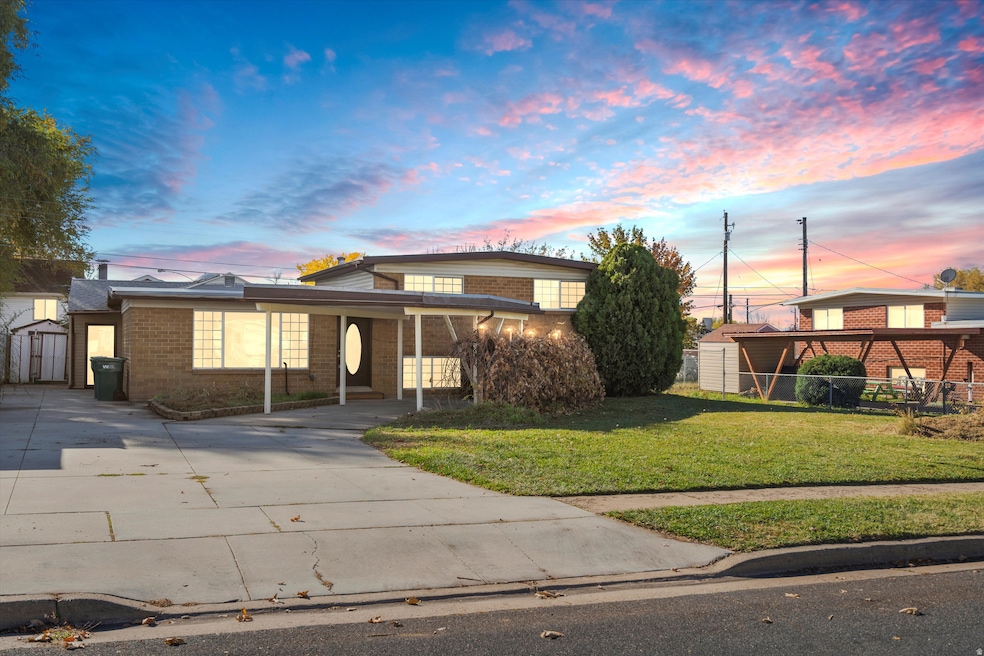 Traditional home featuring concrete driveway, a lawn, brick siding, and a storage unit
