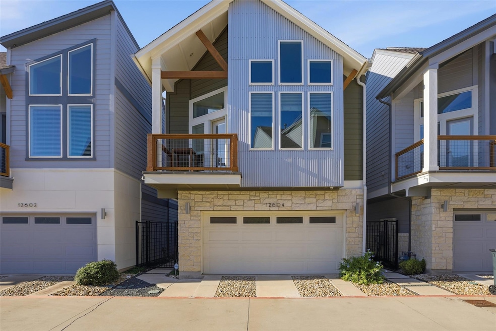 Contemporary home with a balcony, stone siding, concrete driveway, and a garage