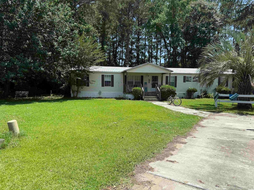 Manufactured / mobile home featuring covered porch, a front lawn, and a metal roof