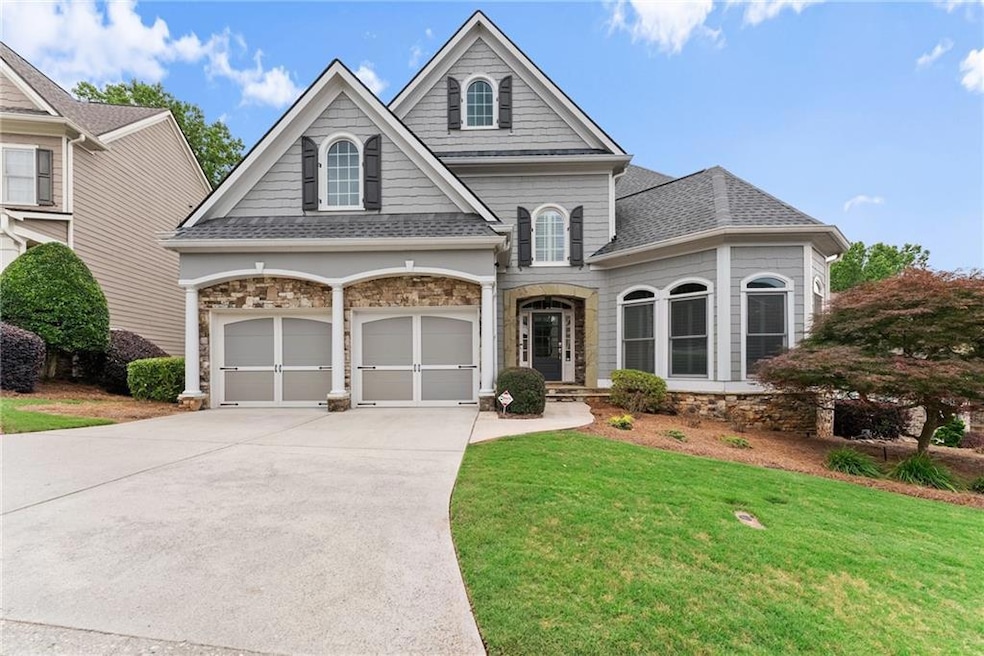 View of front of home with driveway, stone siding, a front lawn, and a garage