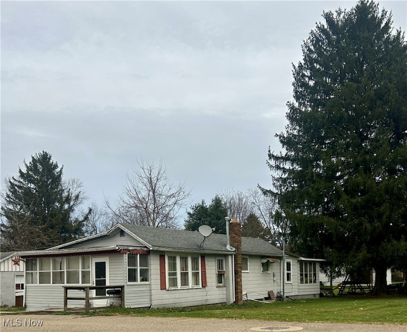 Rear view of house with a chimney and a yard