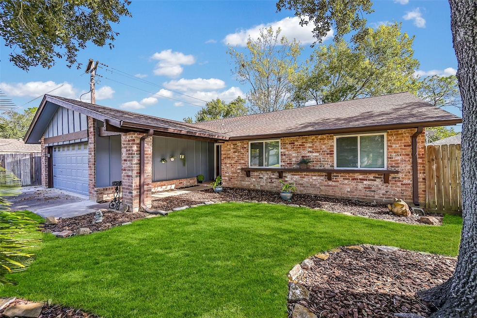 Charming single-story brick home with a well-maintained front yard, featuring mature trees and landscaped garden beds. The attached garage and welcoming entryway offer convenience and curb appeal.
