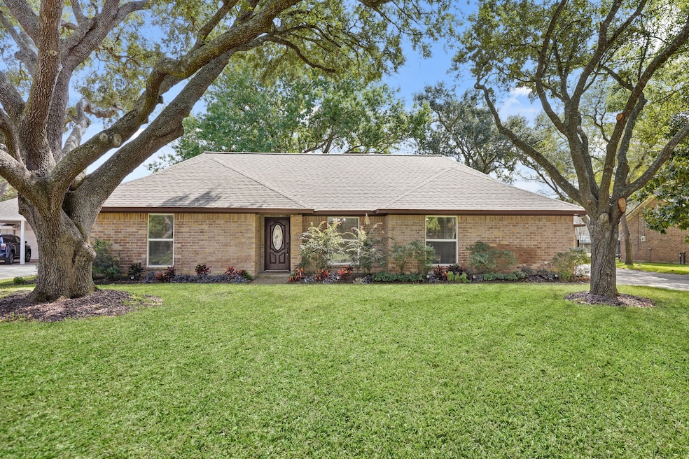 Timeless single-story brick home framed by graceful oaks and a welcoming front entry.