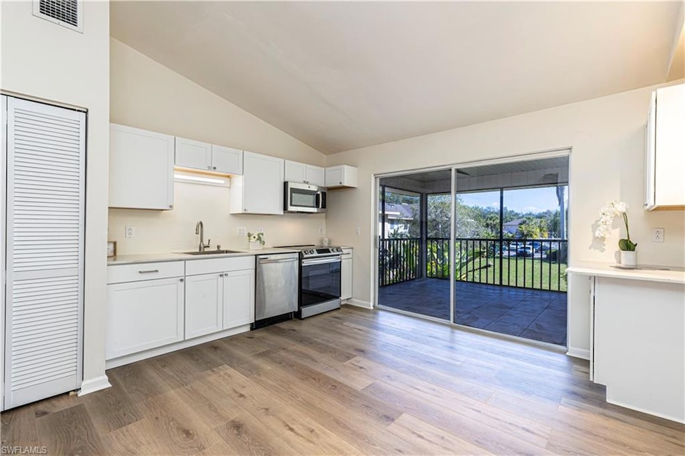 Kitchen with white cabinetry, appliances with stai