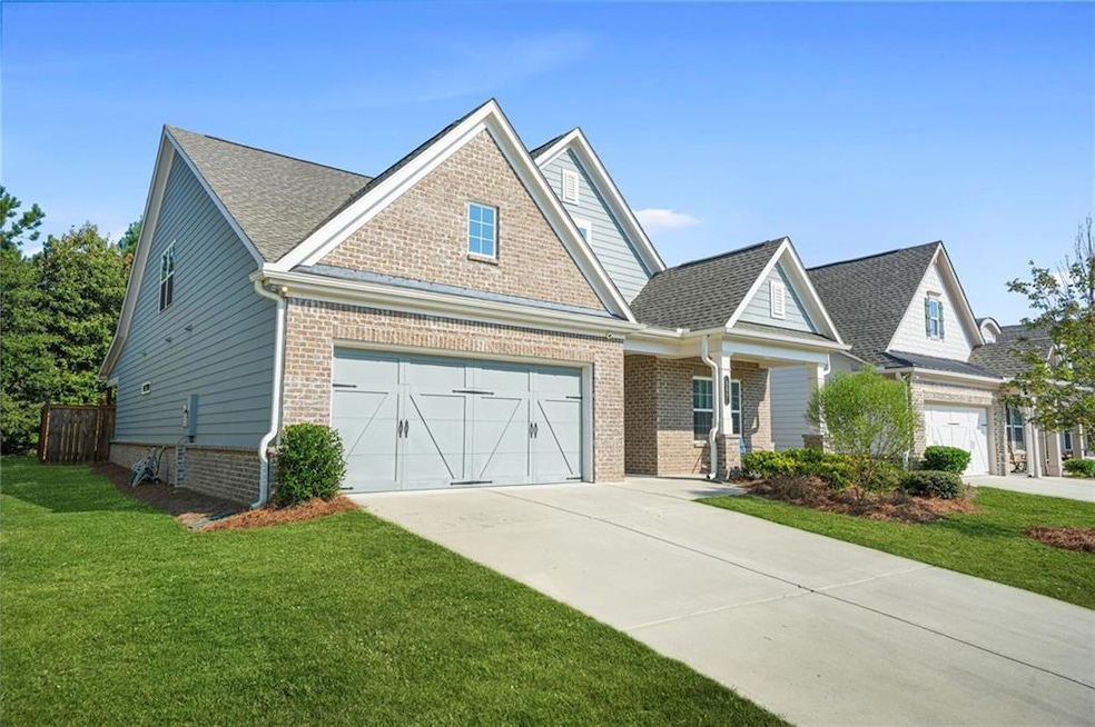 View of front facade with a garage, concrete driveway, a front yard, brick siding, and roof with shingles