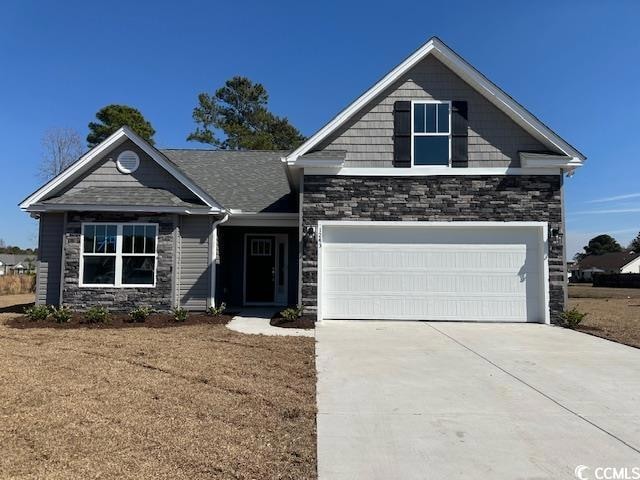 Craftsman-style home featuring stone siding and driveway