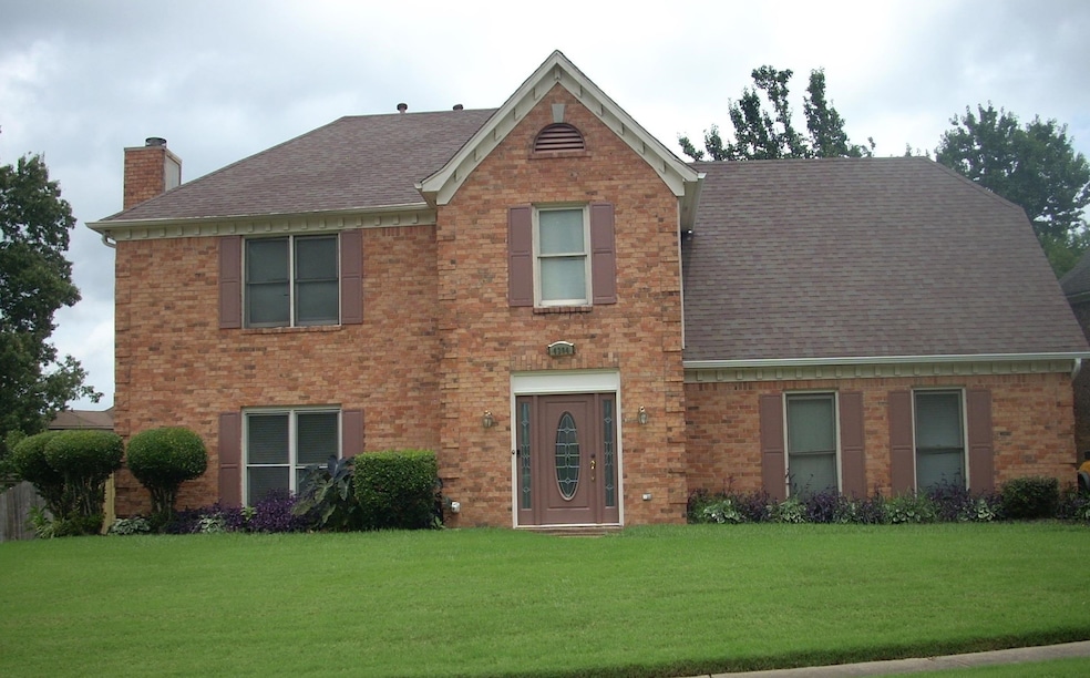 View of front of property featuring a chimney, a shingled roof, brick siding, and a front lawn
