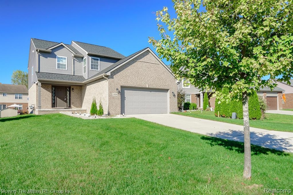Traditional-style home with a front lawn, driveway, brick siding, and an attached garage