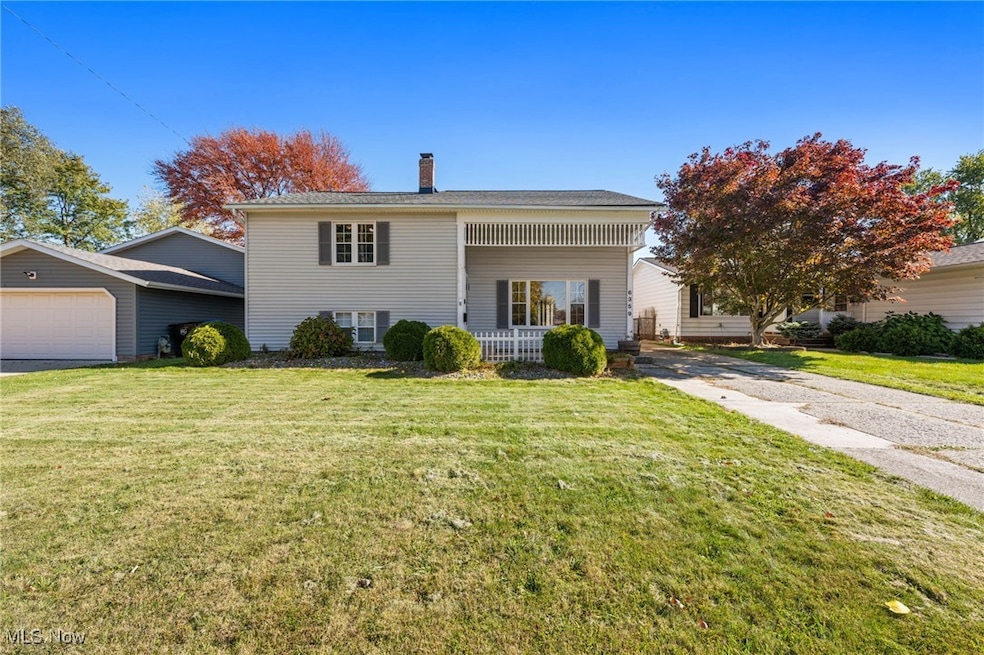 View of front of home featuring a chimney, a front yard, covered porch, and a garage
