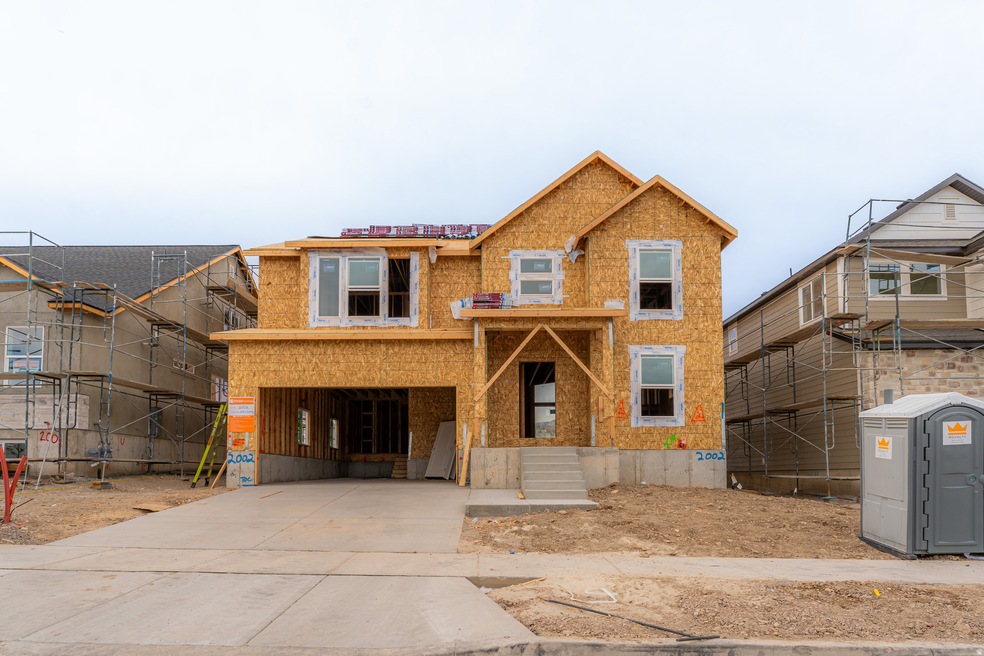 Unfinished property featuring driveway, a porch, and brick siding