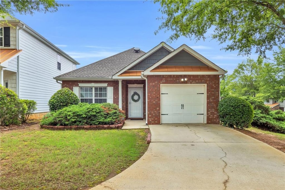 View of front of home with brick siding, driveway, a front yard, and roof with shingles