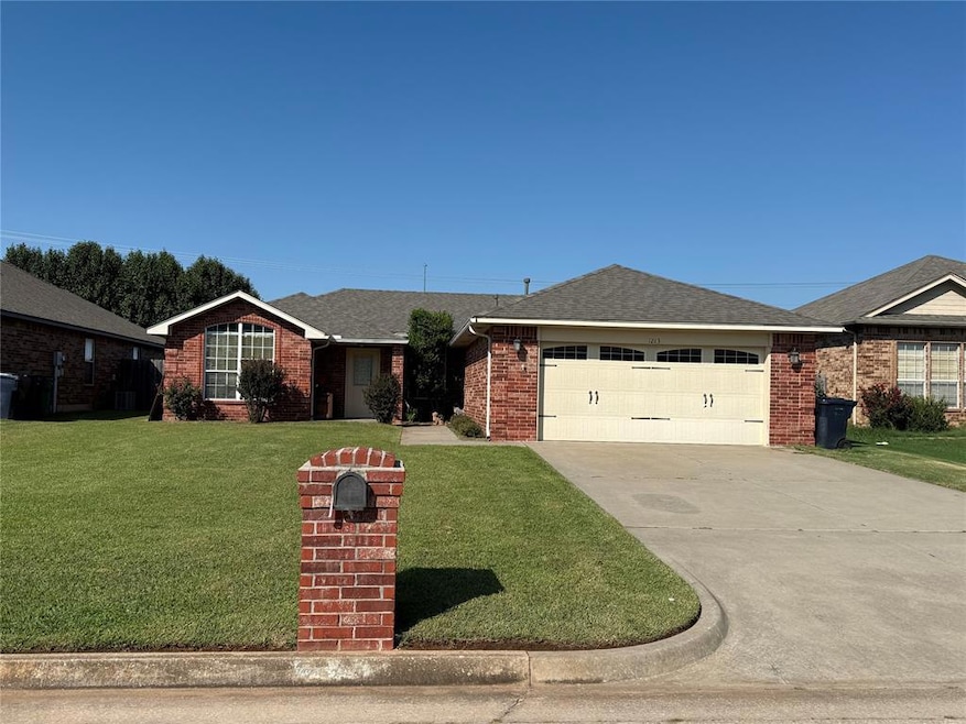 Ranch-style home featuring a shingled roof, a front lawn, driveway, brick siding, and an attached garage