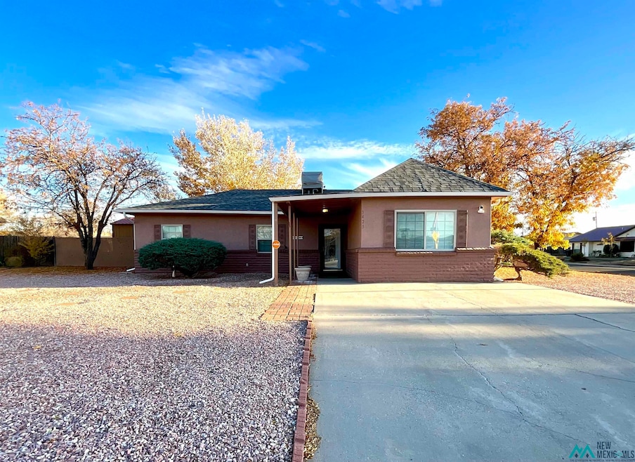 View of front of home featuring stucco siding, a shingled roof, brick siding, and driveway